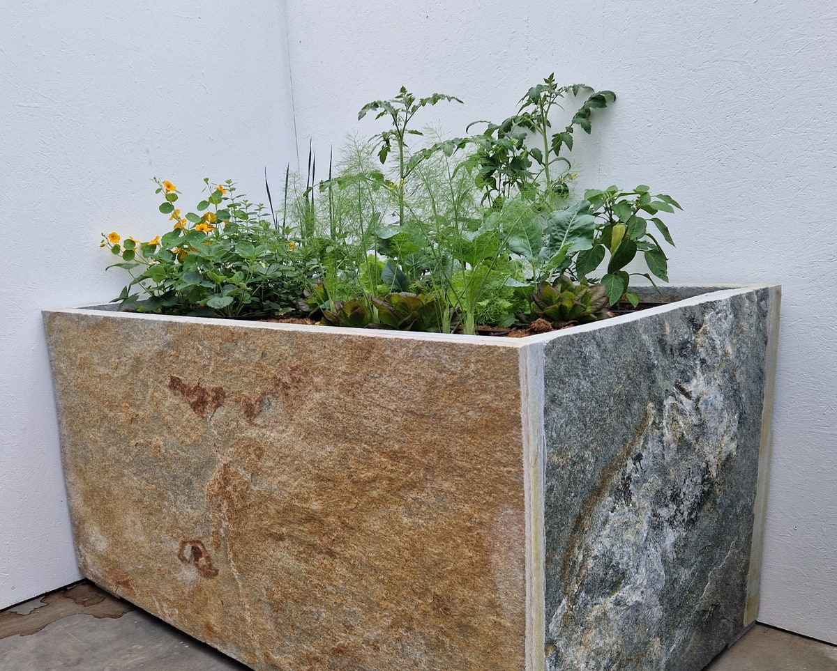 Hochbeet aus beigen Krustenplatten mit Kräutern