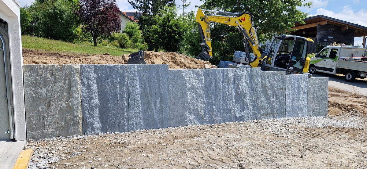 Hohe Mauer aus grauen Krustenplatten im Bau